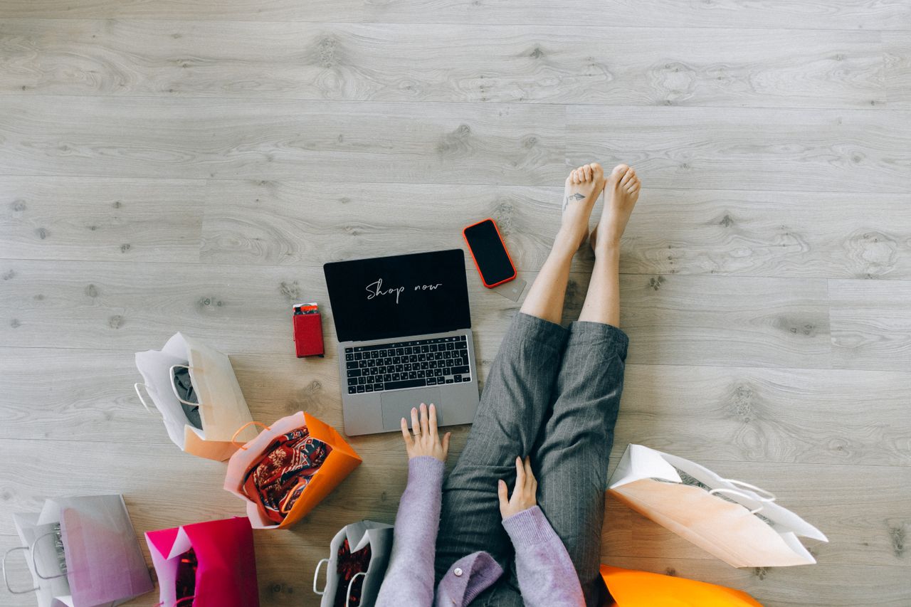 our-story Woman shopping online with laptop and paper bags from above view.