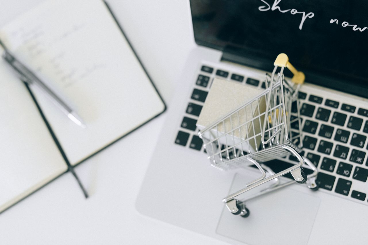 services-bg Creative depiction of online shopping with a miniature cart on a laptop keyboard.